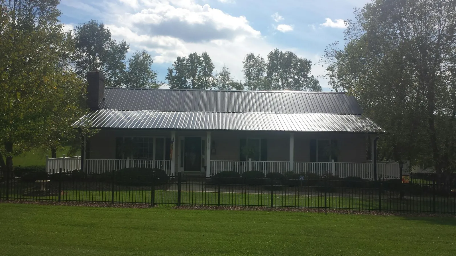 Gray metal roof on a brick ranch with a full width front porch — Gutter Guard Installation work by our crew in Madison